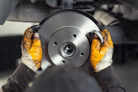 Mechanic fitting a new brake disc to a car