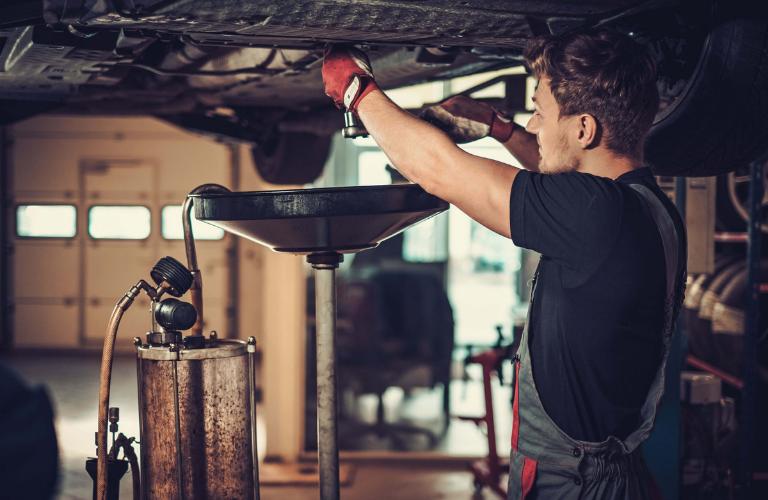 Oil change being carried out under a raised car